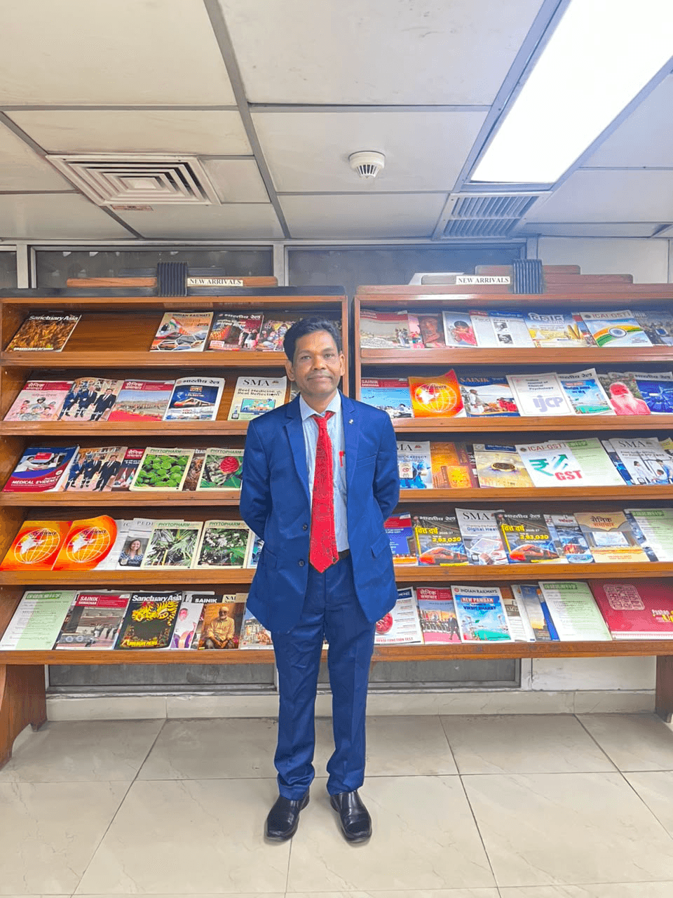 Prof. (Dr.) Mayadhar Barik standing in front of a library magazine display