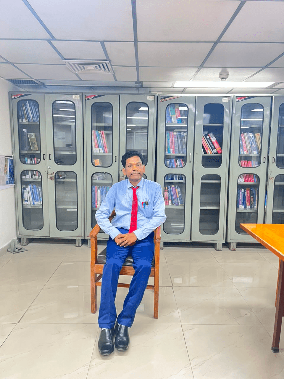Prof. (Dr.) Mayadhar Barik seated in front of library bookshelves